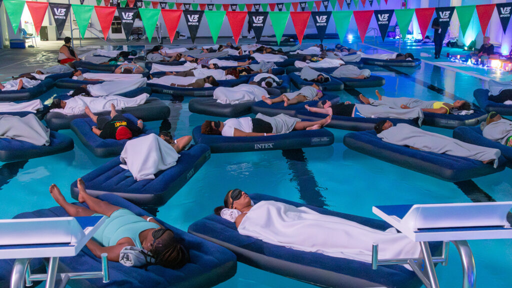 Guests resting on floats across the V3 Sports pool during Floating Soundbath MPLS