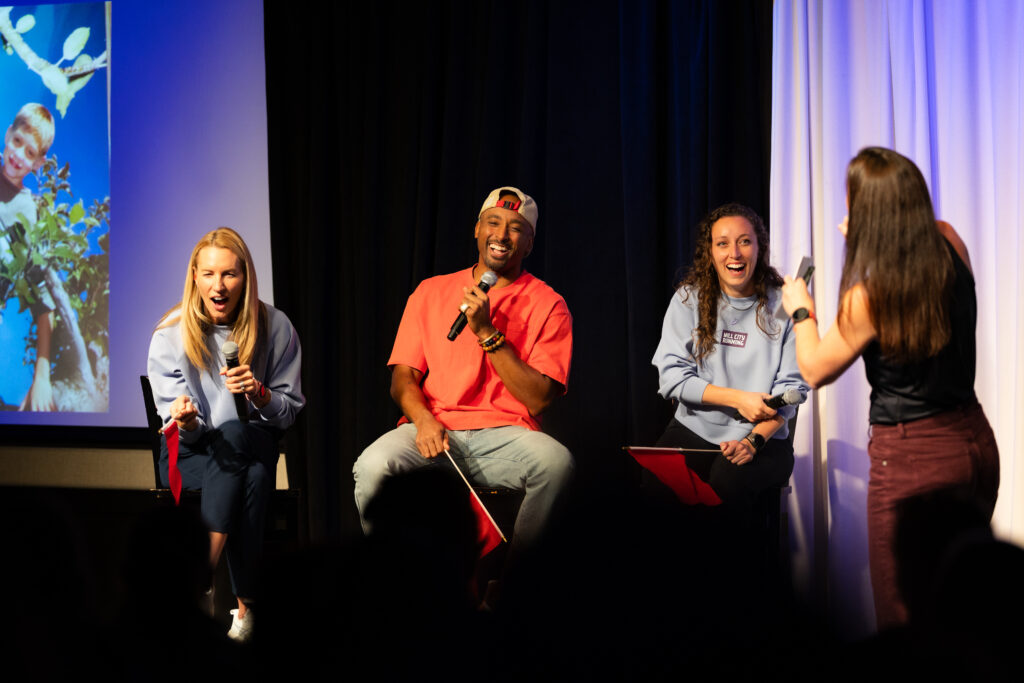 Bruce Brilliance with a microphone alongside fellow contestants on the Twin Cities Game Show stage