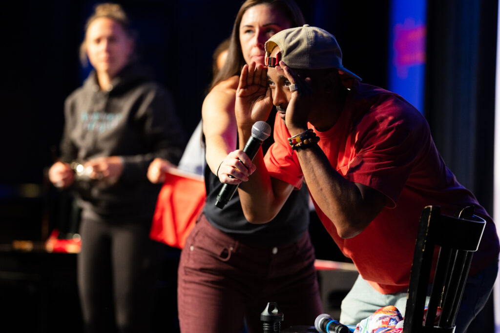 Bruce Brilliance performing into a microphone during the Twin Cities Game Show
